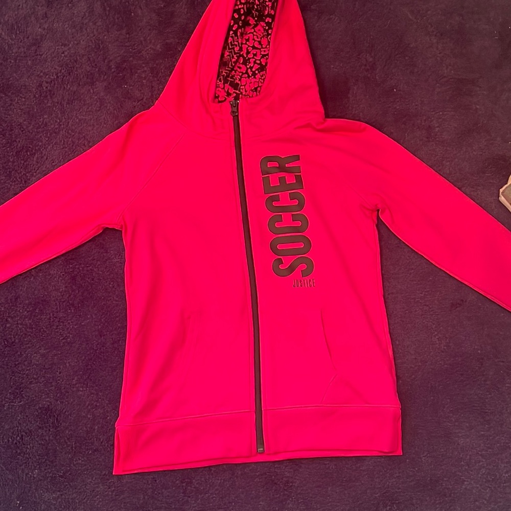 Girls justice zip up hoodie, pink with black writing and holes for thumb.